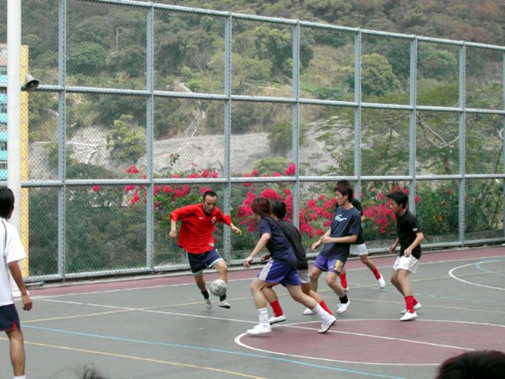 圖中所見，是一位紅色球衣的學長對抗著三位藍色球衣的防守。球技精湛。